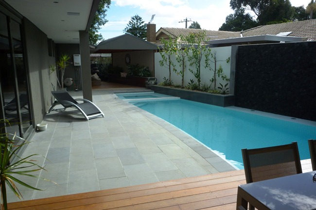 Rectangular natural bluestone pavers installed along a modern backyard swimming pool in a Melbourne home